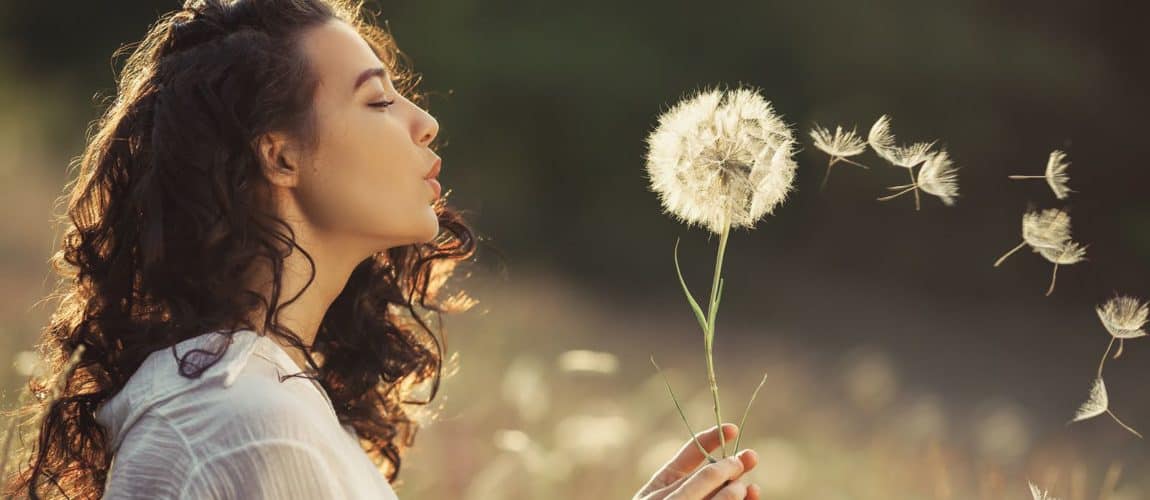 Beautiful Young Woman Sitting On The Field In Green Grass woman with a flower