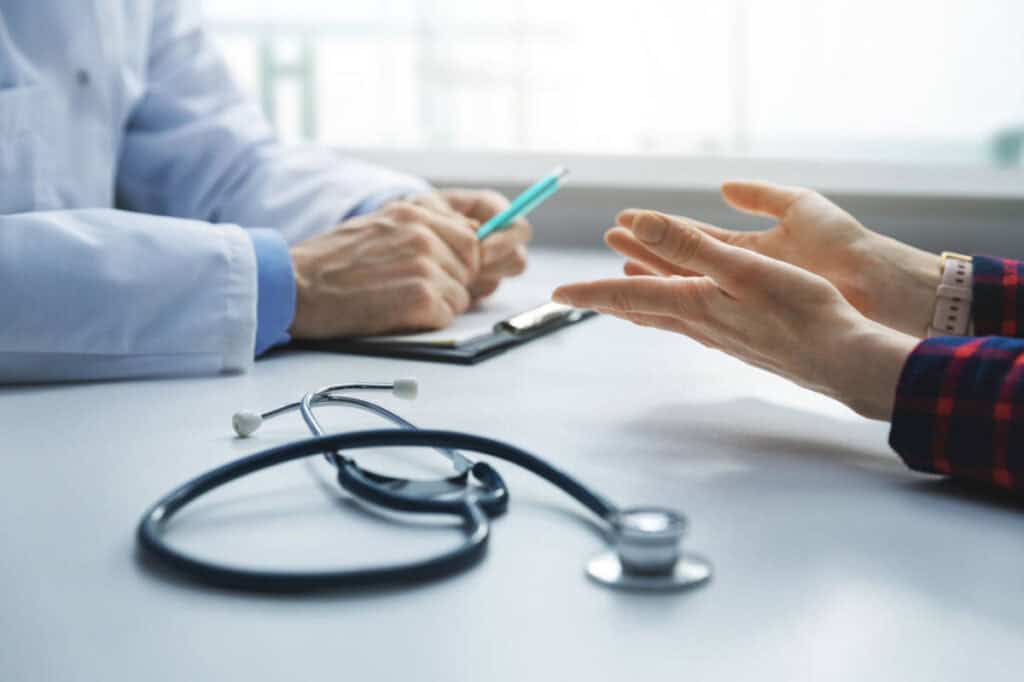 medical consultation - patient in clinic office asks the doctor for advice. focus on woman hands